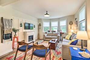 A cozy living room with a fireplace, a sofa, and a coffee table. - Pet-friendly Saranac Lake Retreat w/ Deck & Yard (Saranac Lake)