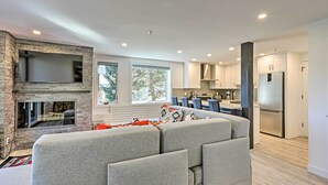 Una cocina moderna con electrodomésticos integrados, un revestimiento de piedra en la pared y un ventanal grande.