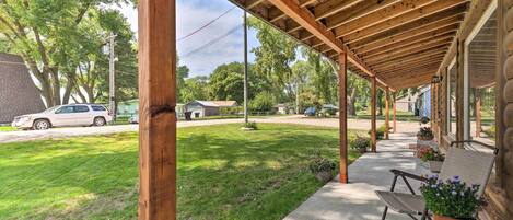 A covered porch with a wooden ceiling, a concrete floor, and a view of a residential street.