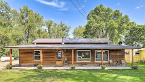 A wooden cabin with a porch, a large window, and a satellite dish.
