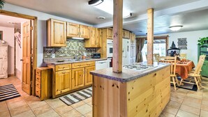 A kitchen with wooden cabinets, a central island, and a dining area with a table and chairs.