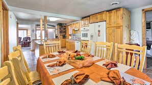 A dining area with a table set for four, wooden chairs, and a kitchen in the background.
