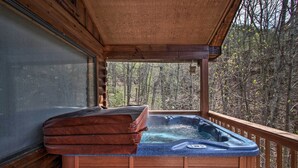 Ein Whirlpool auf einer Holzterrasse mit Blick auf einen Wald.
