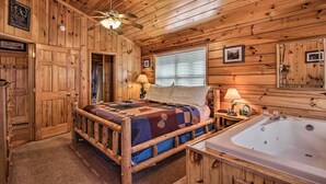 Ein Schlafzimmer einer Holzhütte mit einem Bett, einem Nachttisch, einer Lampe, einem Fenster mit Jalousien und einer Holzkον.