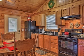 A wooden cabin kitchen with a refrigerator, microwave, stove, and wooden cabinets.