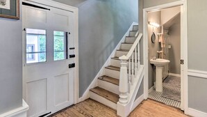 A staircase with a white handrail and wooden steps, leading to a bathroom with a sink and vanity. - Historic Townhome in Downtown Shepherdstown! (Shepherdstown)
