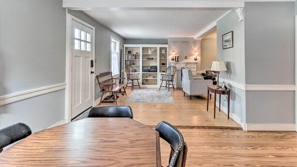 A spacious living room with a wooden dining table and chairs, a fireplace, and a bookshelf. - Historic Townhome in Downtown Shepherdstown! (Shepherdstown)