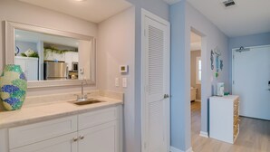 A modern kitchen with white cabinets, a stainless steel refrigerator, and a large mirror above the sink. - Beach Access, Walk to Golf! Gulf Shores Condo (Gulf Shores)