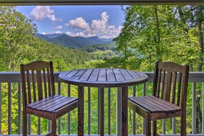 A wooden deck with two chairs and a table, overlooking a mountainous landscape with a lake and forested hills. - Mountain Escape w/ Stunning Views! (Franklin)