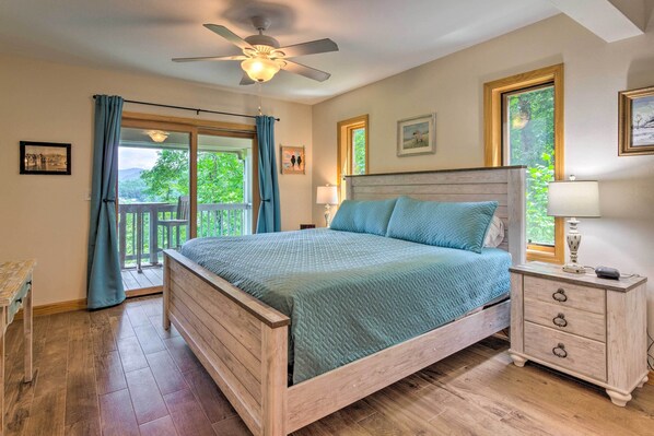 A bedroom with a wooden bed, a nightstand, a ceiling fan, and a view through a glass door to the outdoors. - Mountain Escape w/ Stunning Views! (Franklin)