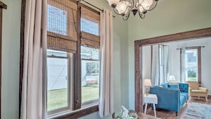 A living room with a blue sofa, a wooden coffee table, and a chandelier. - Lake Charles Cottage w/ Fireplace & Yard! (Lake Charles)