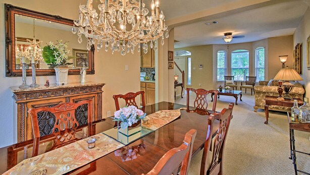 A dining area with a large wooden table, chairs, a chandelier, and a mirror above the table. - Home w/ Patio, Mins to Seaworld+lackland Afb! (San Antonio)