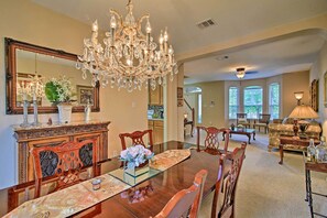 A dining area with a large wooden table, chairs, a chandelier, and a mirror above the table. - Home w/ Patio, Mins to Seaworld+lackland Afb! (San Antonio)