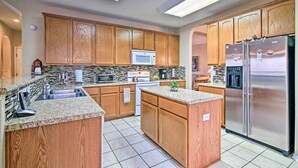 A kitchen with wooden cabinets, a stainless steel refrigerator, and a granite countertop. - Home w/ Patio, Mins to Seaworld+lackland Afb! (San Antonio)