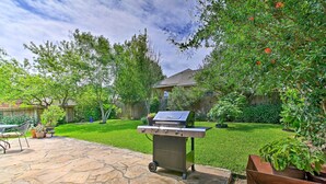 A backyard with a stone patio, a grill, and a wooden fence. - Home w/ Patio, Mins to Seaworld+lackland Afb! (San Antonio)
