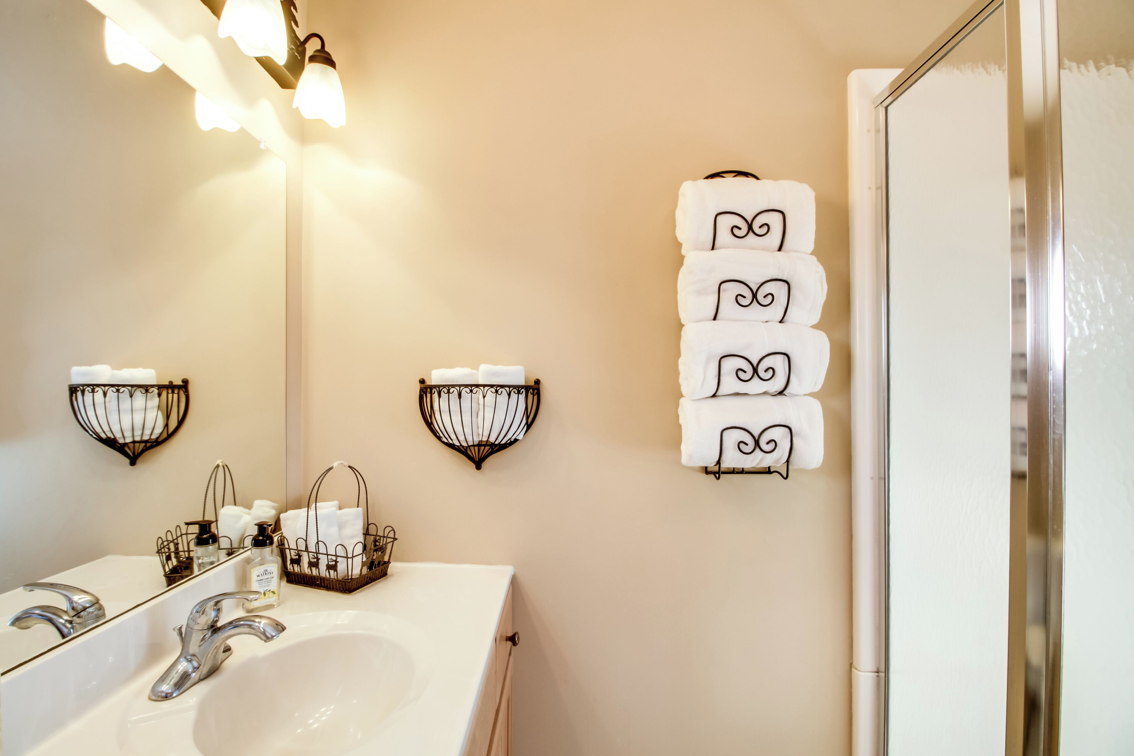 A bathroom with a white sink, two wall-mounted towel racks, and a mirror.