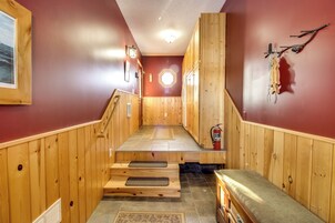 Interior de madera con una escalera que sube a un nivel superior, un extintor en la pared y un banco en la parte inferior.