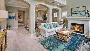 A spacious living room with a fireplace, a white sofa with teal cushions, and a blue patterned rug. - Oceanside Home w/ Rooftop Patio, Walk to Beach! (Oceanside)