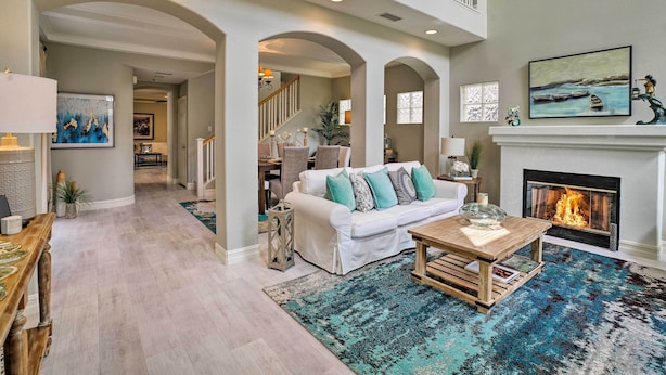 A spacious living room with a fireplace, a white sofa with teal cushions, and a blue patterned rug. - Oceanside Home w/ Rooftop Patio, Walk to Beach! (Oceanside)
