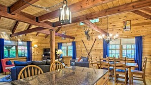 L’intérieur d’une cabane en rondins, avec un îlot central en granit, une table à manger en bois et des rideaux bleus.