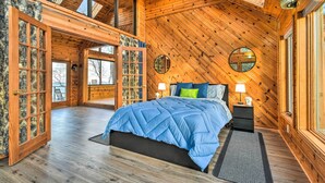 Un dormitorio amplio con una cama grande, paredes de madera y un tragaluz.