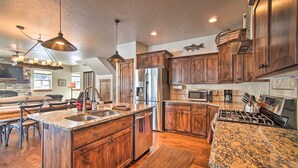 A spacious kitchen with granite countertops, wooden cabinets, stainless steel appliances, and pendant lighting. - Mccall Home + Hot Tub ~ 2 Mi to Payette Lake (McCall)