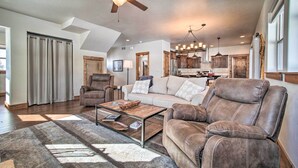 A spacious living room with a leather sofa, a coffee table, and a ceiling fan. - Mccall Home + Hot Tub ~ 2 Mi to Payette Lake (McCall)