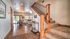 A spacious living area with a wooden staircase, a dining table, and a view of the outdoors. - Mccall Home + Hot Tub ~ 2 Mi to Payette Lake (McCall)
