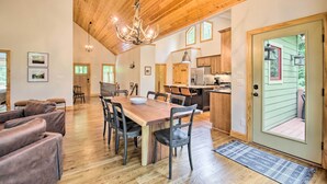 A spacious dining area with a wooden table and chairs, a chandelier, and a view of the kitchen and outdoor area. - Luxe Wintergreen Resort Escape w/ Hot Tub! (Nellysford)