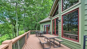 A wooden deck with picnic tables and chairs, surrounded by lush greenery. - Luxe Wintergreen Resort Escape w/ Hot Tub! (Nellysford)