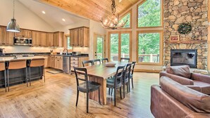 A spacious kitchen with wooden cabinets, a dining area with a large table and chairs, and a stone fireplace. - Luxe Wintergreen Resort Escape w/ Hot Tub! (Nellysford)