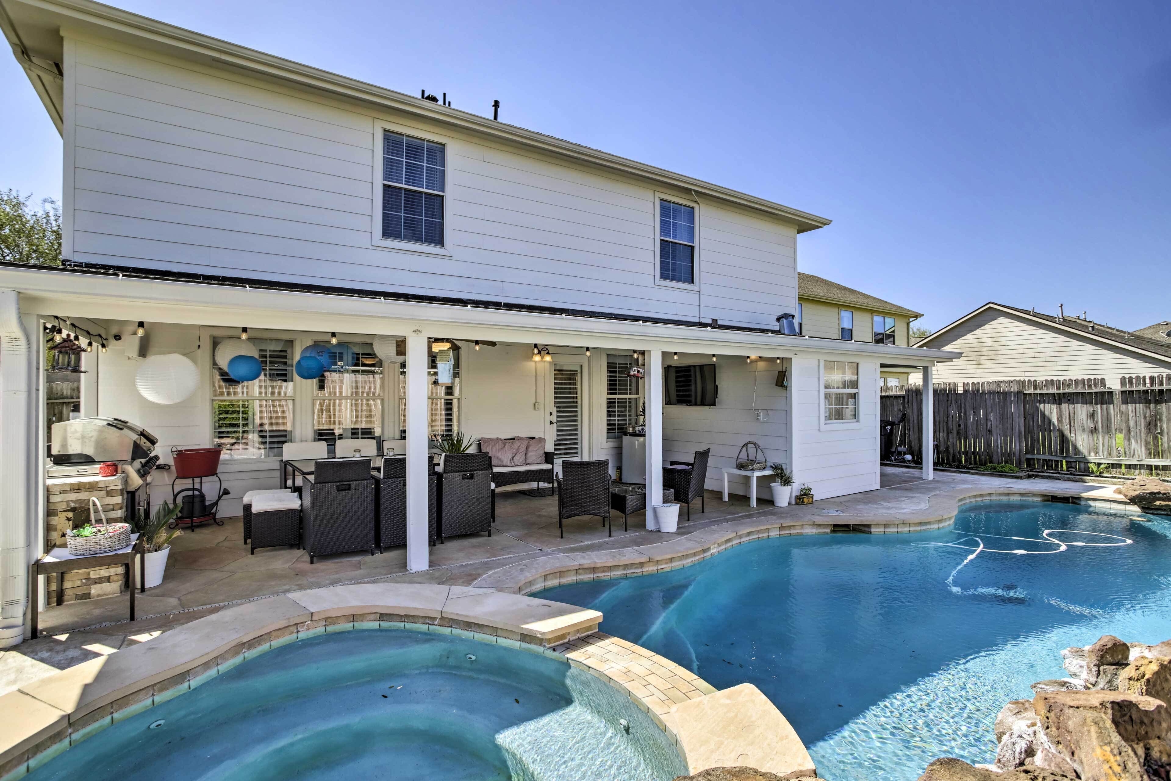 A house with a covered patio area, a swimming pool, and outdoor furniture.