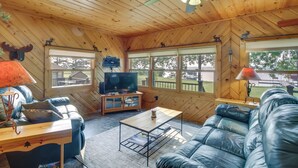 A cozy cabin interior with a wooden ceiling, a leather sofa, a television, and a dining table. - Large Home on Lake Edward w/ Deck & Fire Pit! (Nisswa)