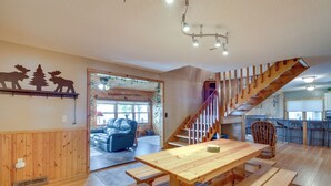 A spacious living area with a wooden dining table, benches, and a staircase leading to an upper level. - Large Home on Lake Edward w/ Deck & Fire Pit! (Nisswa)