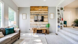 Un salon moderne avec un meuble mural en bois, un canapé, une table basse et un escalier menant à une autre pièce.