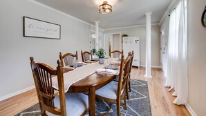 Une salle à manger avec une table en bois, des chaises et un lustre.