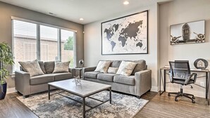 A modern living room with two grey sofas, a coffee table, and a world map on the wall. - Modern Indianapolis Home w/ Skyline Views (Indianapolis)
