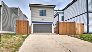 A residential building with a garage, wooden fences, and a concrete driveway. - Modern Indianapolis Home w/ Skyline Views (Indianapolis)