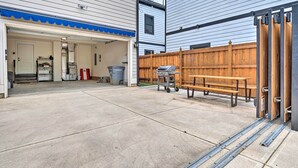 A garage with a blue awning, a wooden fence, a barbecue grill, and a bench. - Modern Indianapolis Home w/ Skyline Views (Indianapolis)
