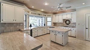 Una cocina amplia con armarios blancos, una isla grande y vistas al exterior.