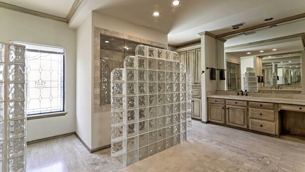 A spacious bathroom with a large mirror, a glass shower enclosure, and a marble floor. - Private Pool: Lakefront Harlingen Home (Harlingen)