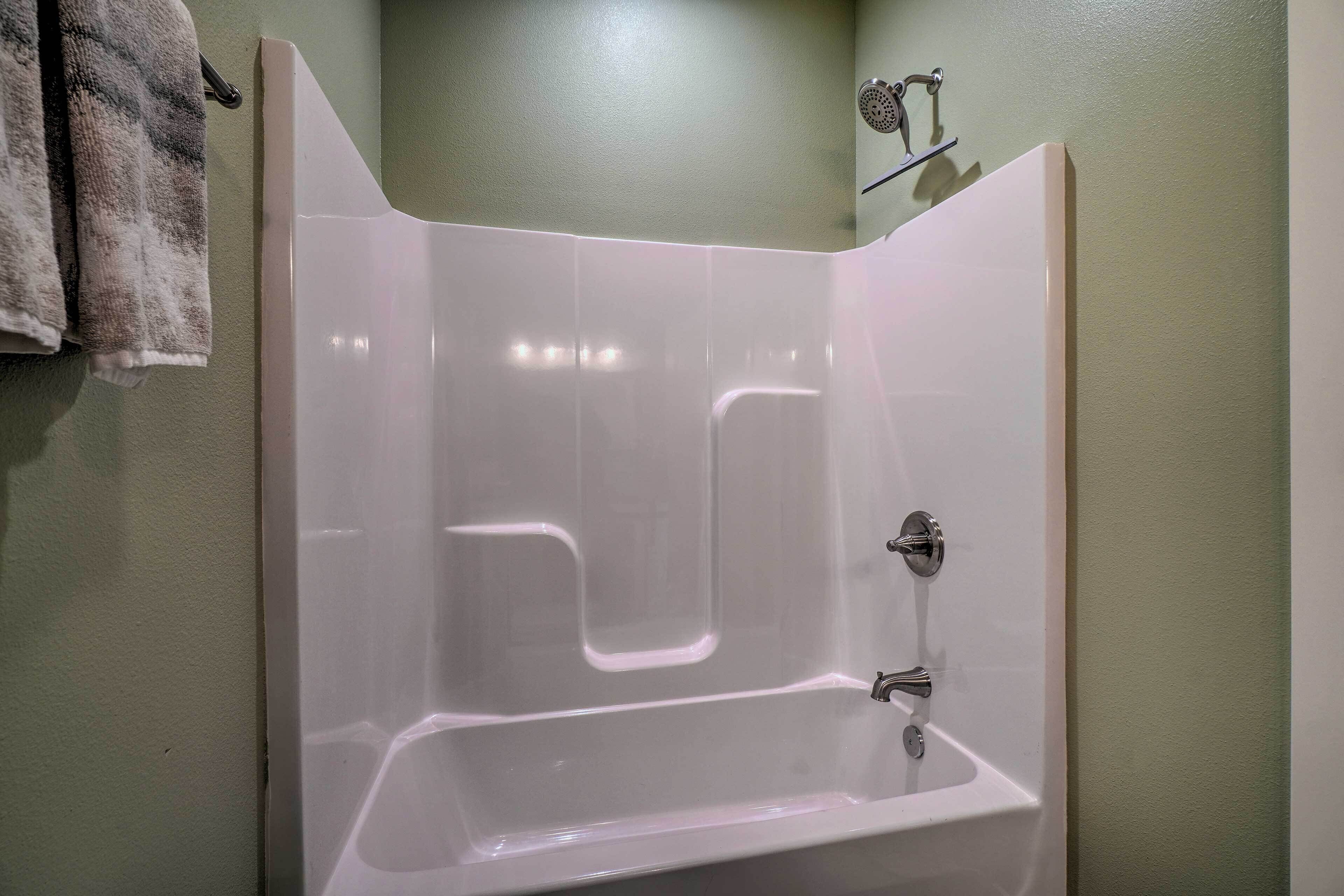 Une salle de bain avec une baignoire blanche, une douche et un lavabo.
