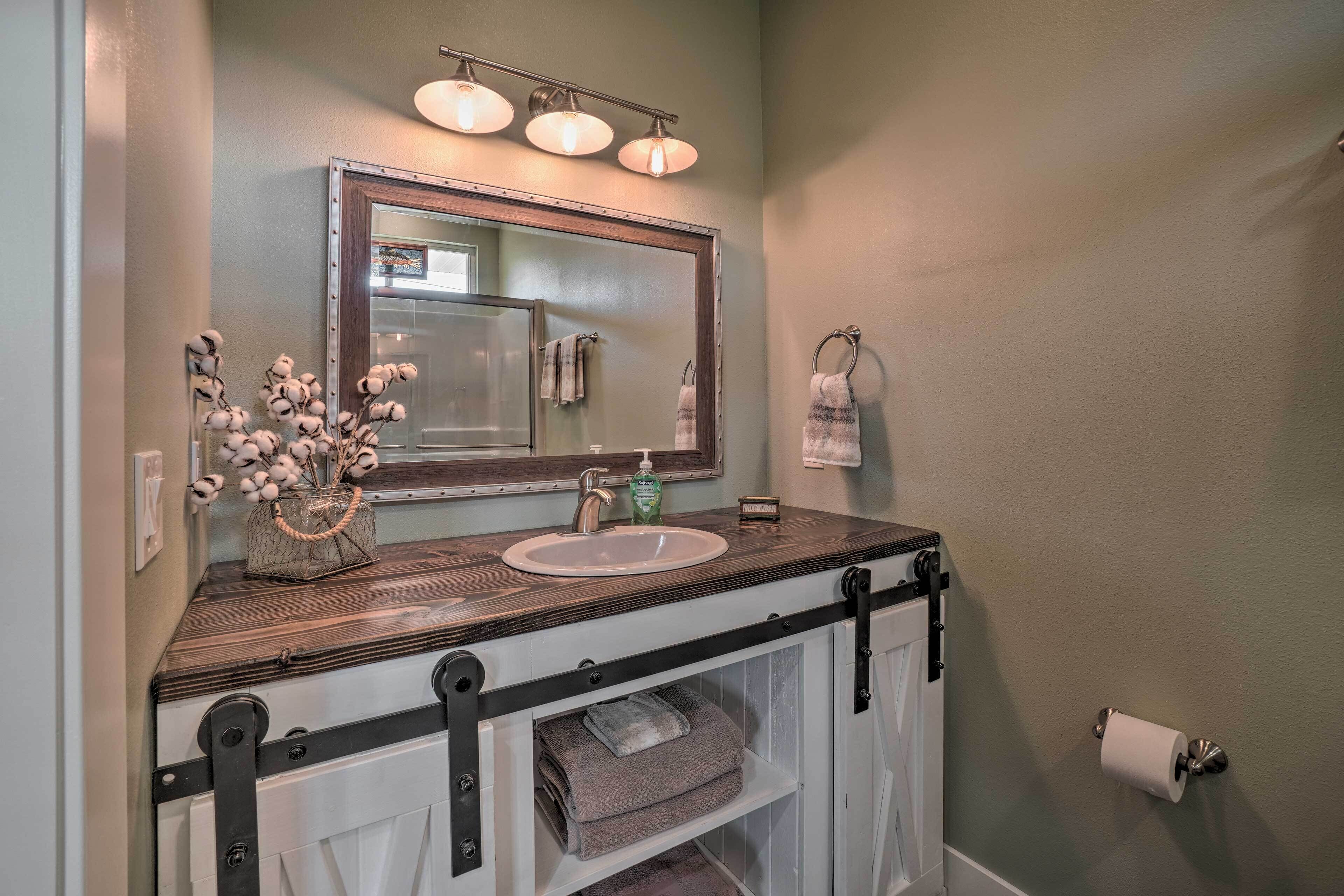 A bathroom with a wooden vanity, a large mirror, and a towel rack.