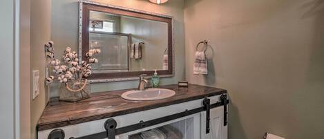A bathroom with a wooden vanity, a large mirror, and a towel rack.