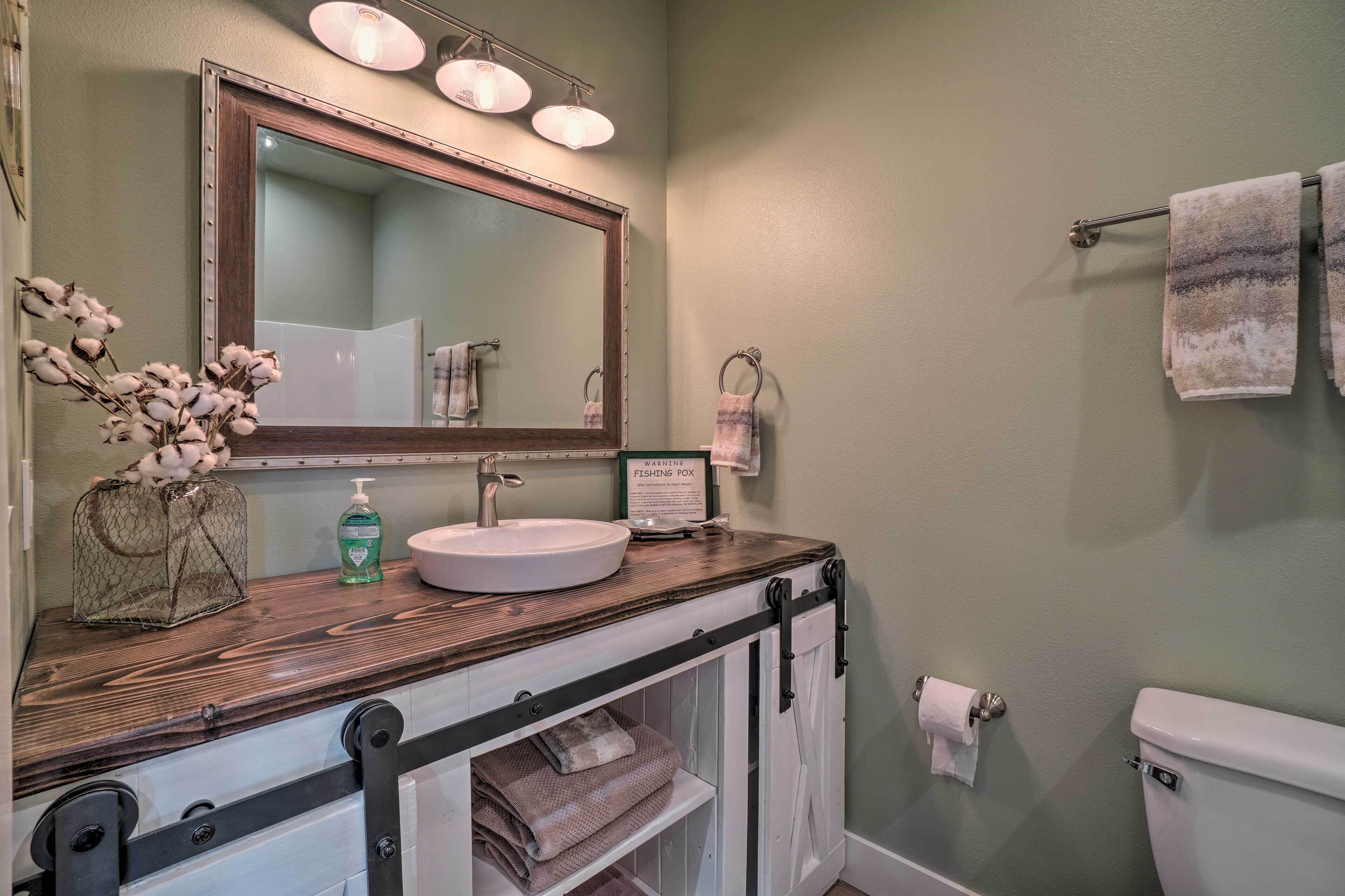 A bathroom with a wooden vanity, a large mirror, a toilet, and a towel rack.