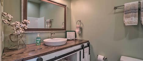 A bathroom with a wooden vanity, a large mirror, a toilet, and a towel rack.