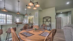 Un comedor con una mesa redonda de madera, seis sillas e iluminación colgante.
