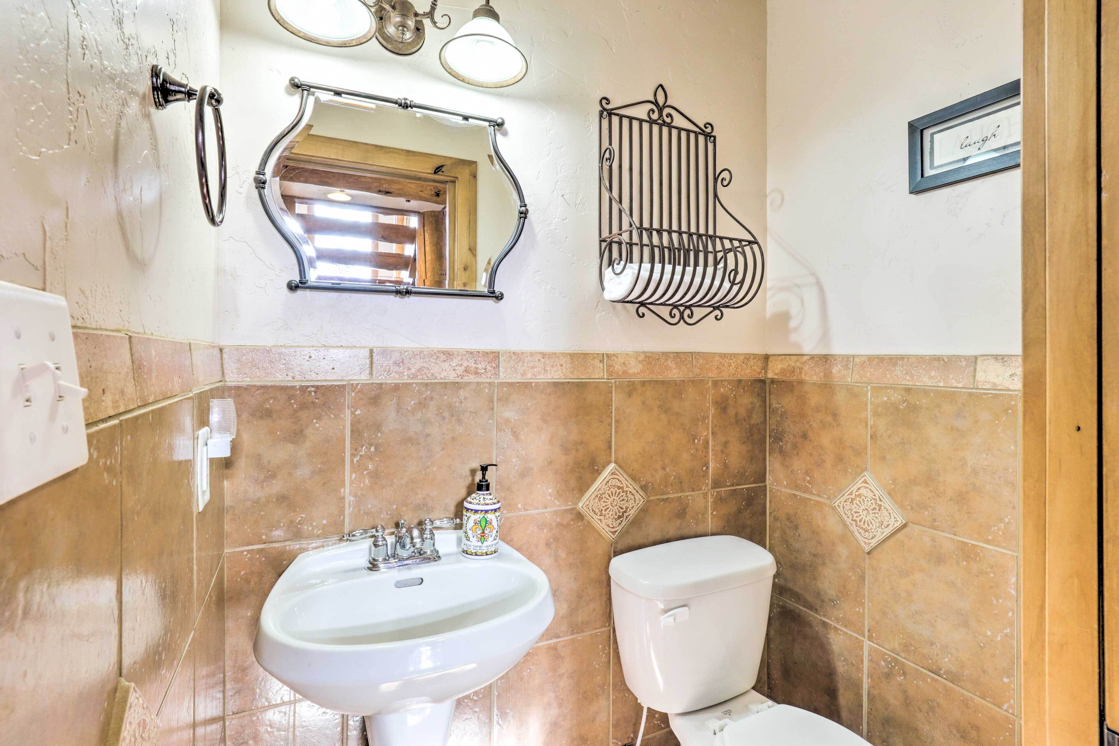 A bathroom with a sink, toilet, and a mirror with a towel rack above it.