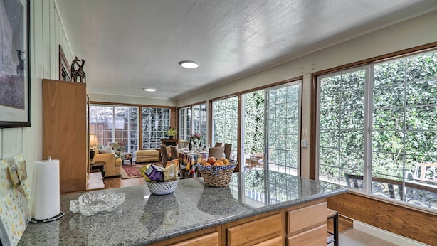 A spacious kitchen with large windows, wooden cabinets, and a granite countertop. - Peaceful Oakland Oasis w/ Private Yard! (Oakland)