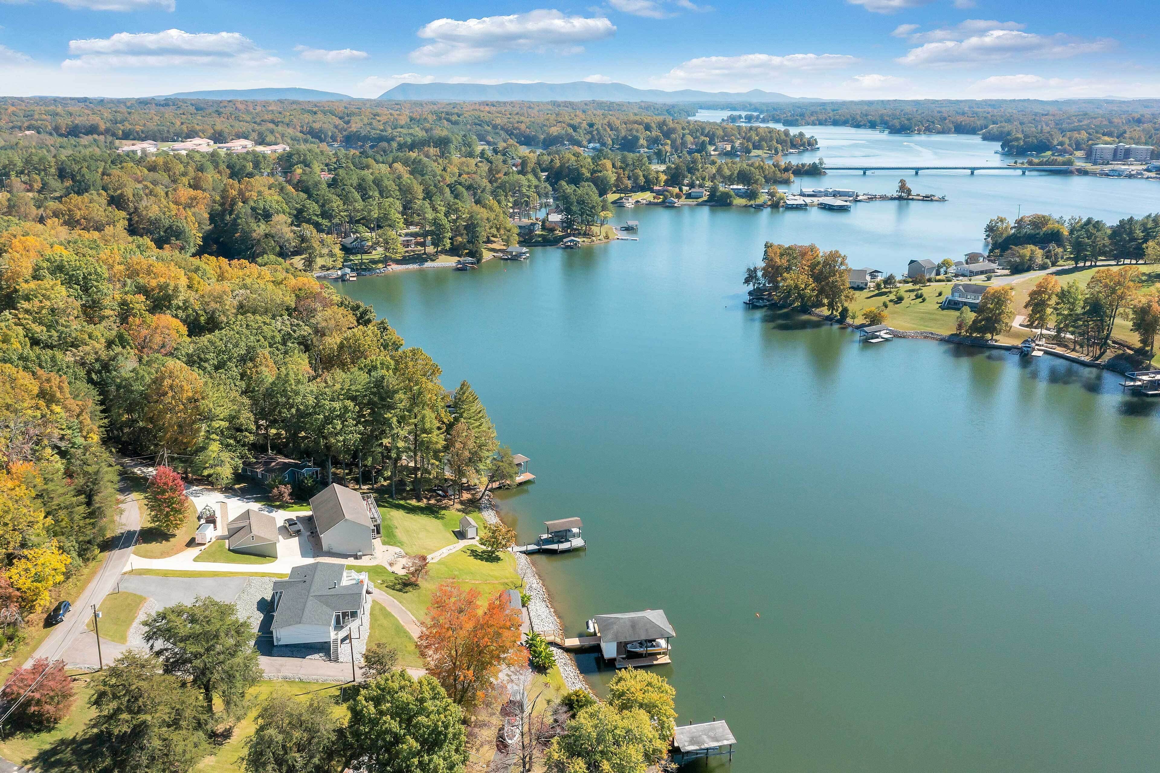 A residential area with houses near a lake, a bridge, and a forested landscape.